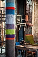 yarn bombing, recouvrement d'un poteau en tricot main de différentes couleurs.